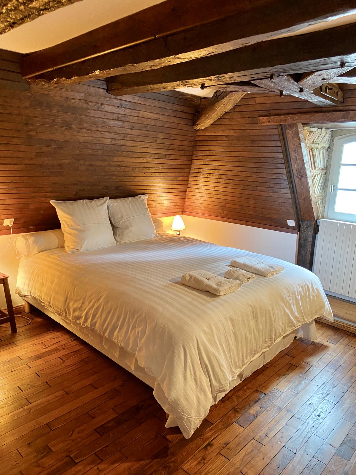 The panelled bedroom at Maison du Seigneur, with oak beams and a mullioned window