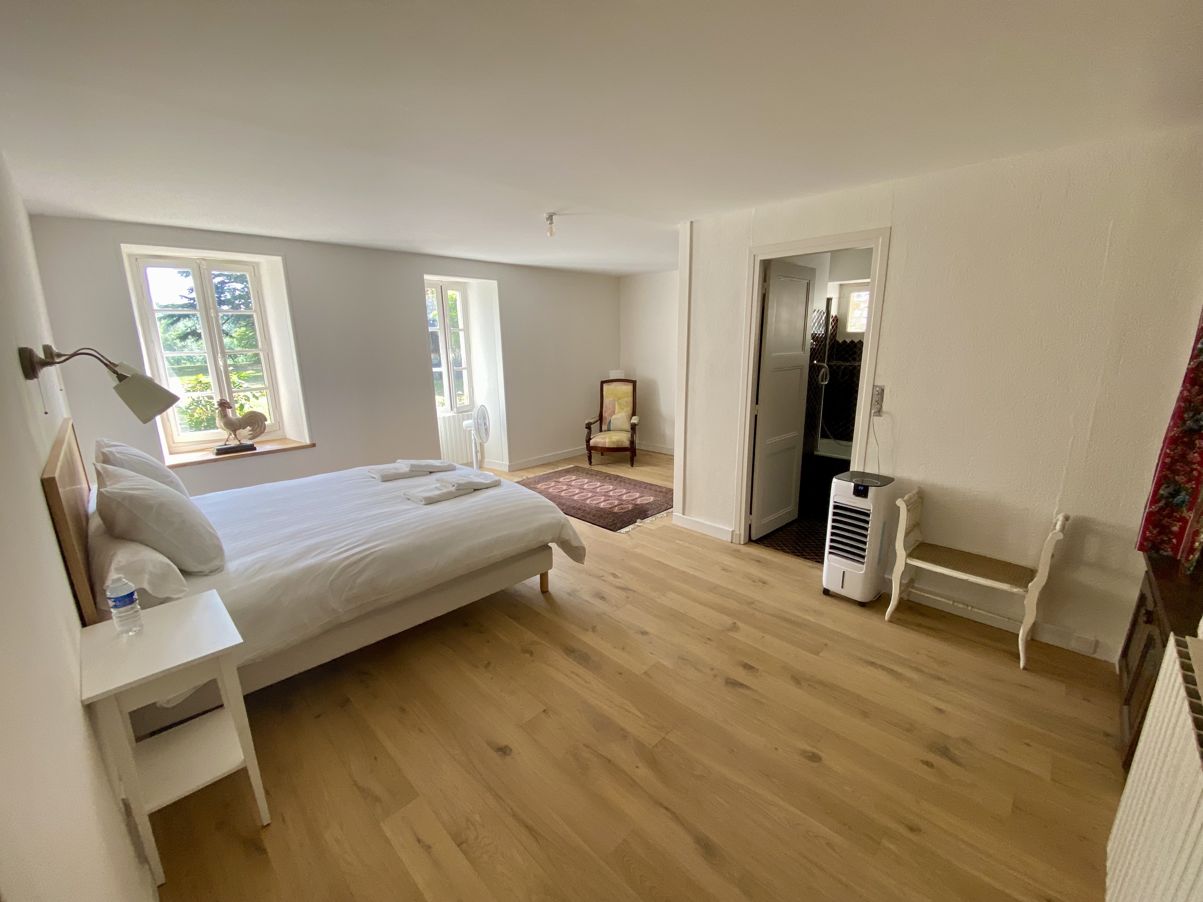 The master bedroom at Maison du Seigneur — king bed, two windows onto the park