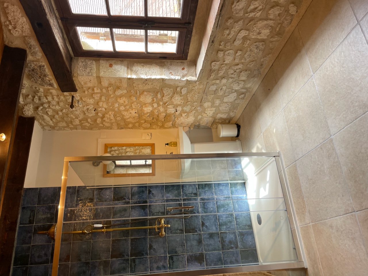 The shower in bedroom one at Maison des Artistes, blue zellige with brass fittings against a stone wall