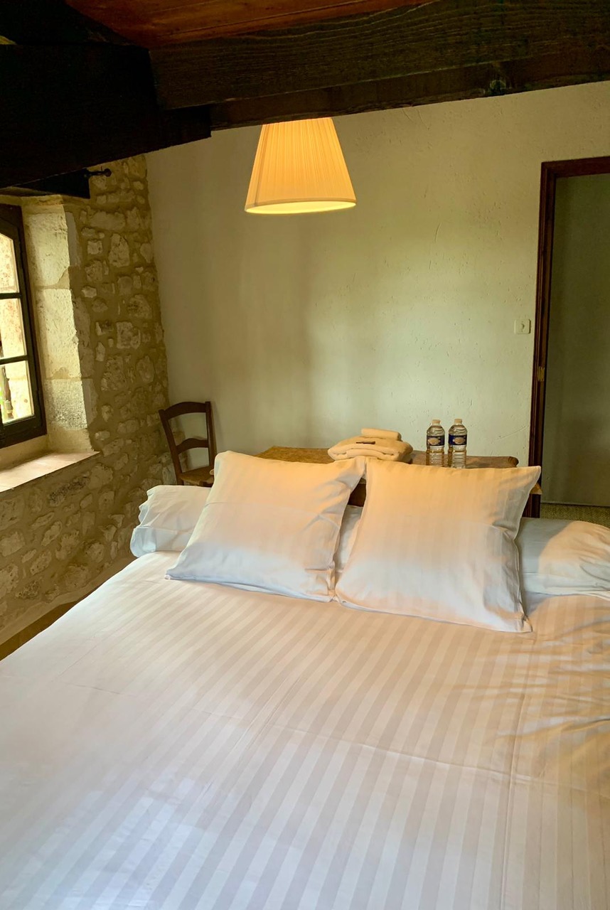 Bedroom two at Maison des Artistes, with a stone wall and beamed ceiling