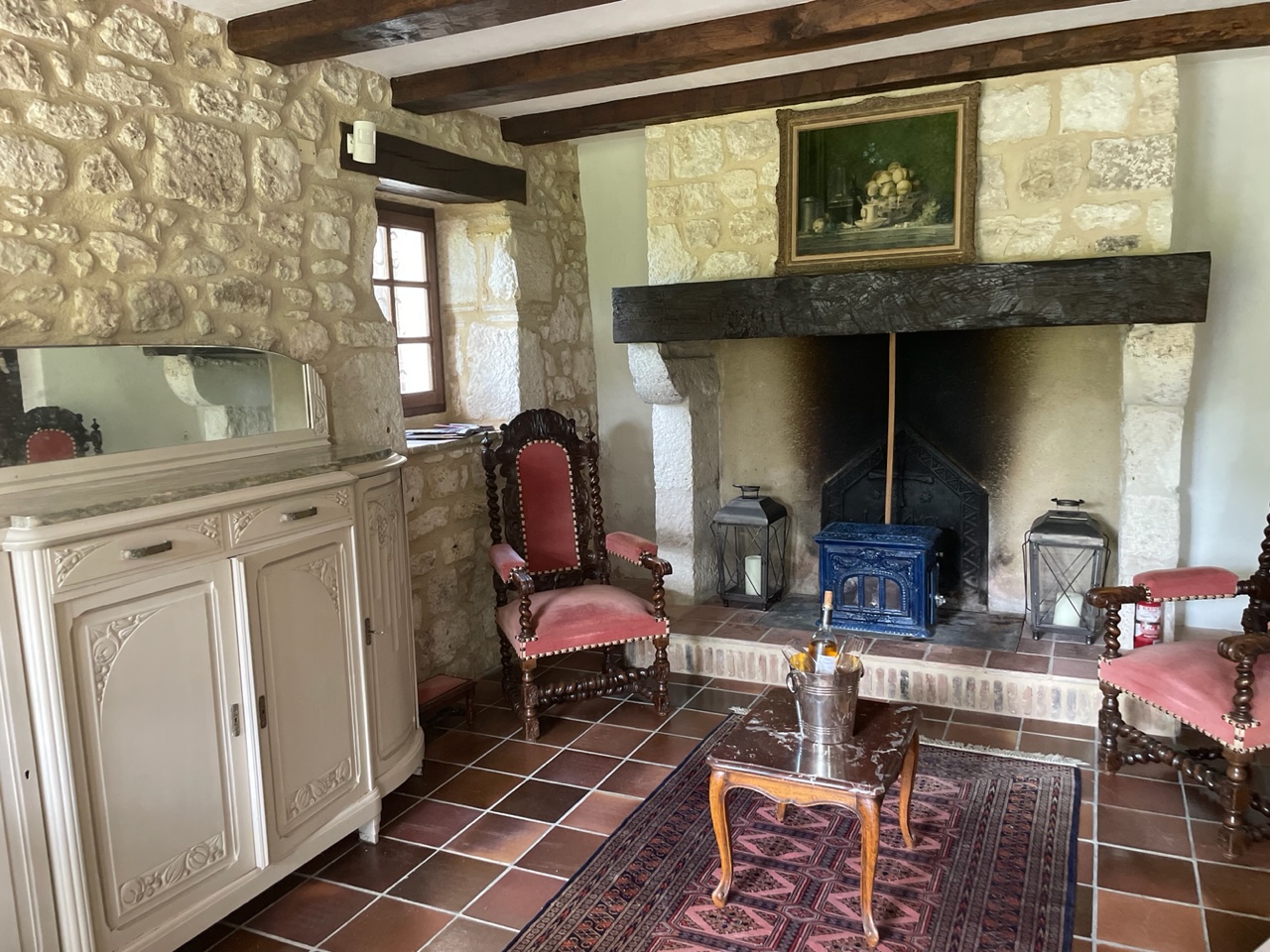 The second sitting room at Maison des Artistes, with a blue enamelled wood burner in a stone hearth
