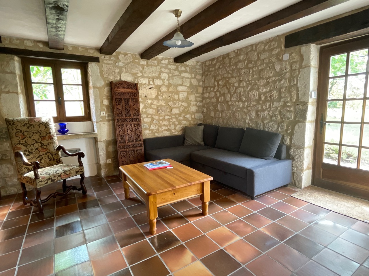 The lounge at Maison des Artistes, with a corner sofa bed and carved Indian door against bare stone