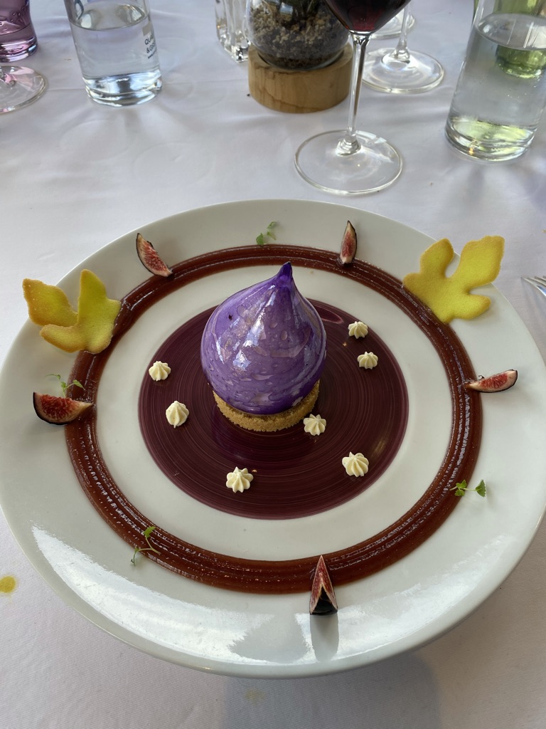 A purple fig dome dessert at La Tour des Vents on a sablé base, with chocolate disc, fig segments and yellow tuiles.