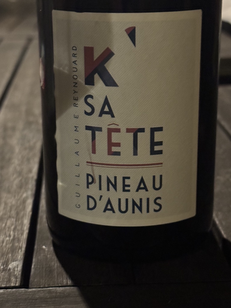 The K' SA TÊTE Pineau d'Aunis bottle by Guillaume Reynouard — close-up of the modern label, red and black typography on cream, on a wooden table
