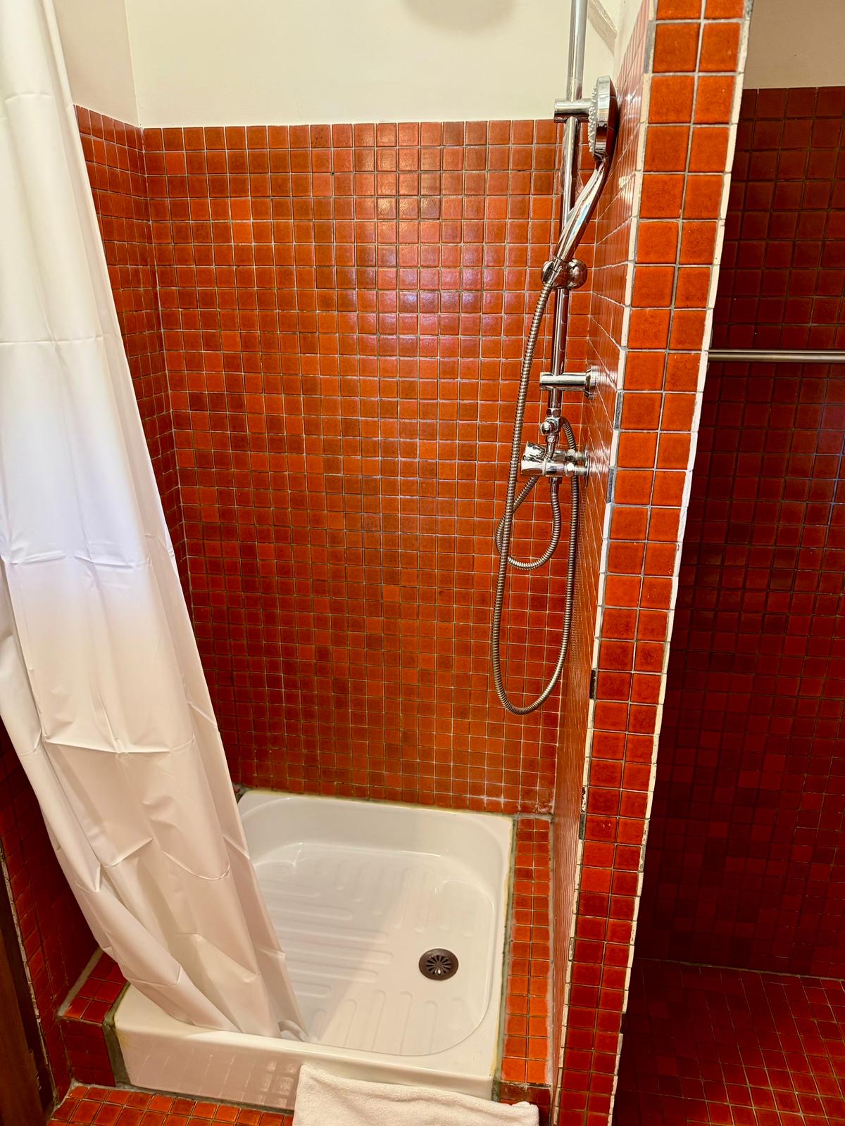 The second floor shower room at Le Pigeonnier, tiled in small red mosaic with a walk-in shower tray
