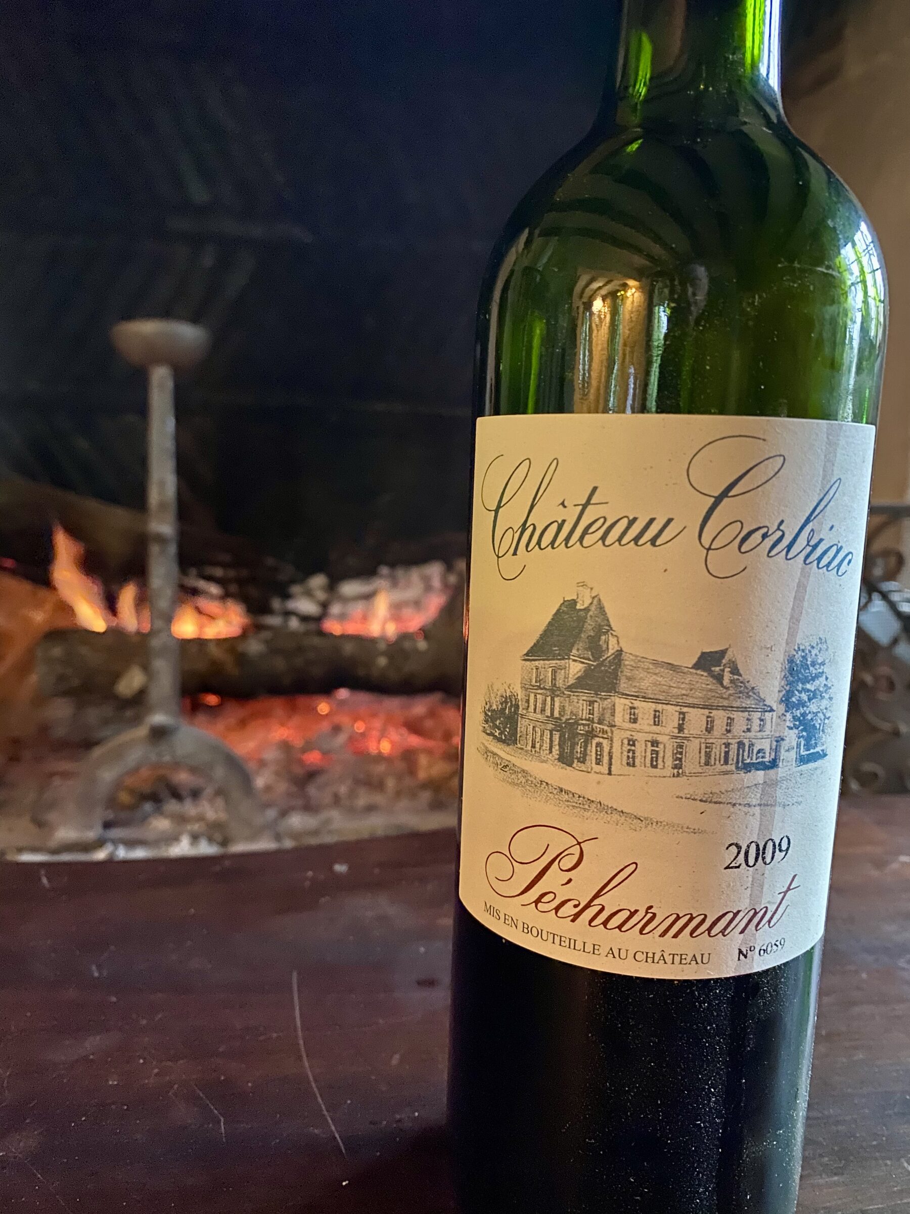 Château Corbiac 2009 Pécharmant — the famous vintage — by the fire at Manoir du Suquet, label lit by the flames, a metal decanter warming beside it