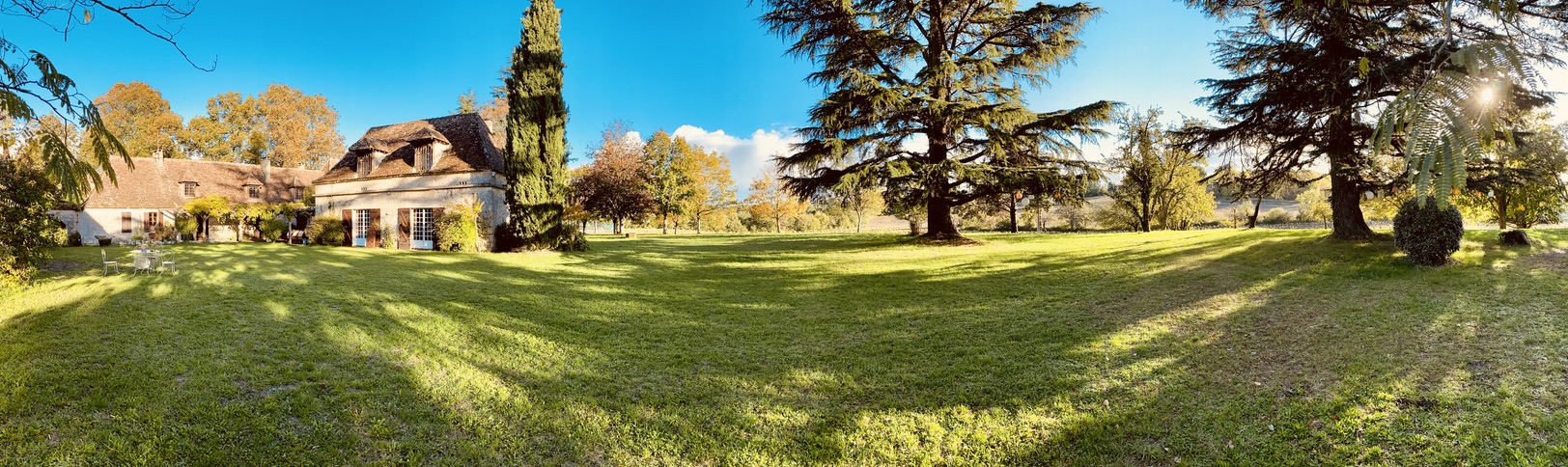 The estate grounds at golden hour — panoramic view across the great lawn with Jardin to the left, cedars and cypresses framing the view, autumn 2020