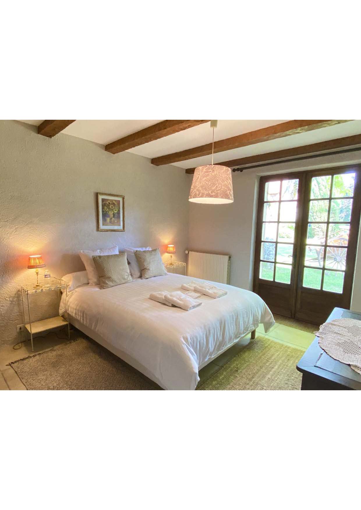 Ground-floor bedroom one at Maison des Tournesols, with French doors onto the lawn
