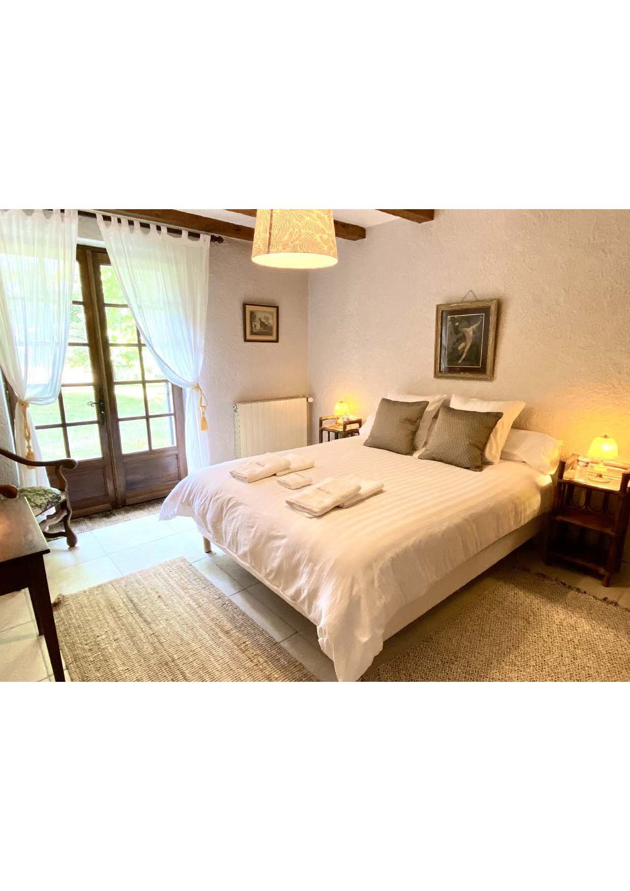 Ground-floor bedroom two at Maison des Tournesols, with tall French doors and voile curtains