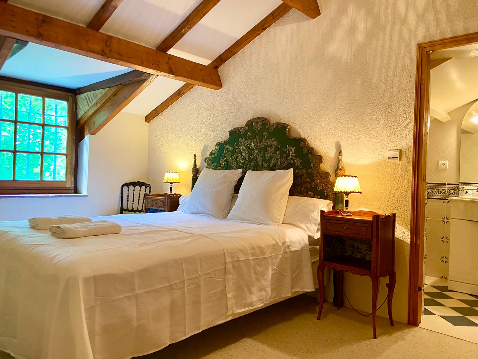 The carved green and gilt headboard in bedroom four at Maison des Tournesols, with the adjoining wash basin room beyond