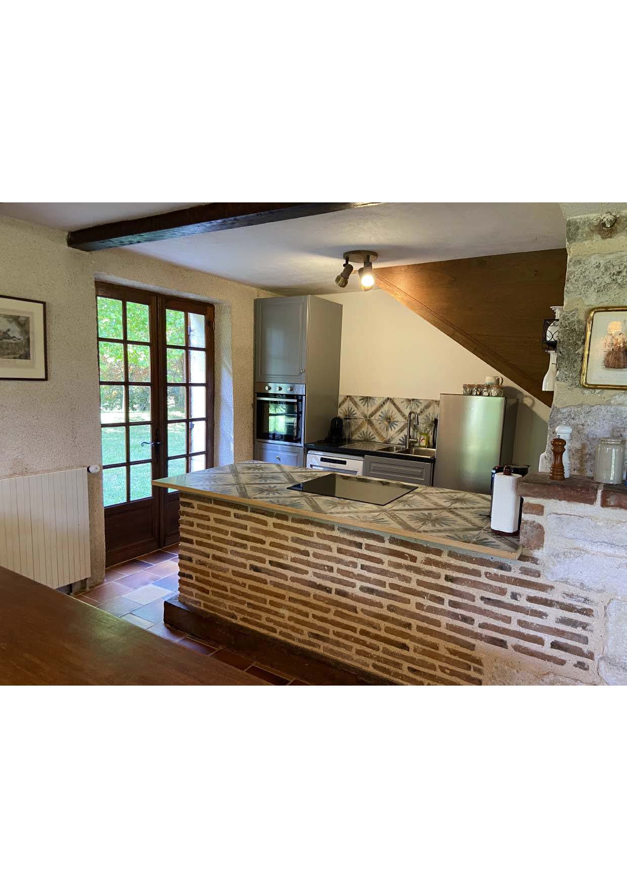 The kitchen at Maison des Tournesols, with induction hob set into a tiled bar