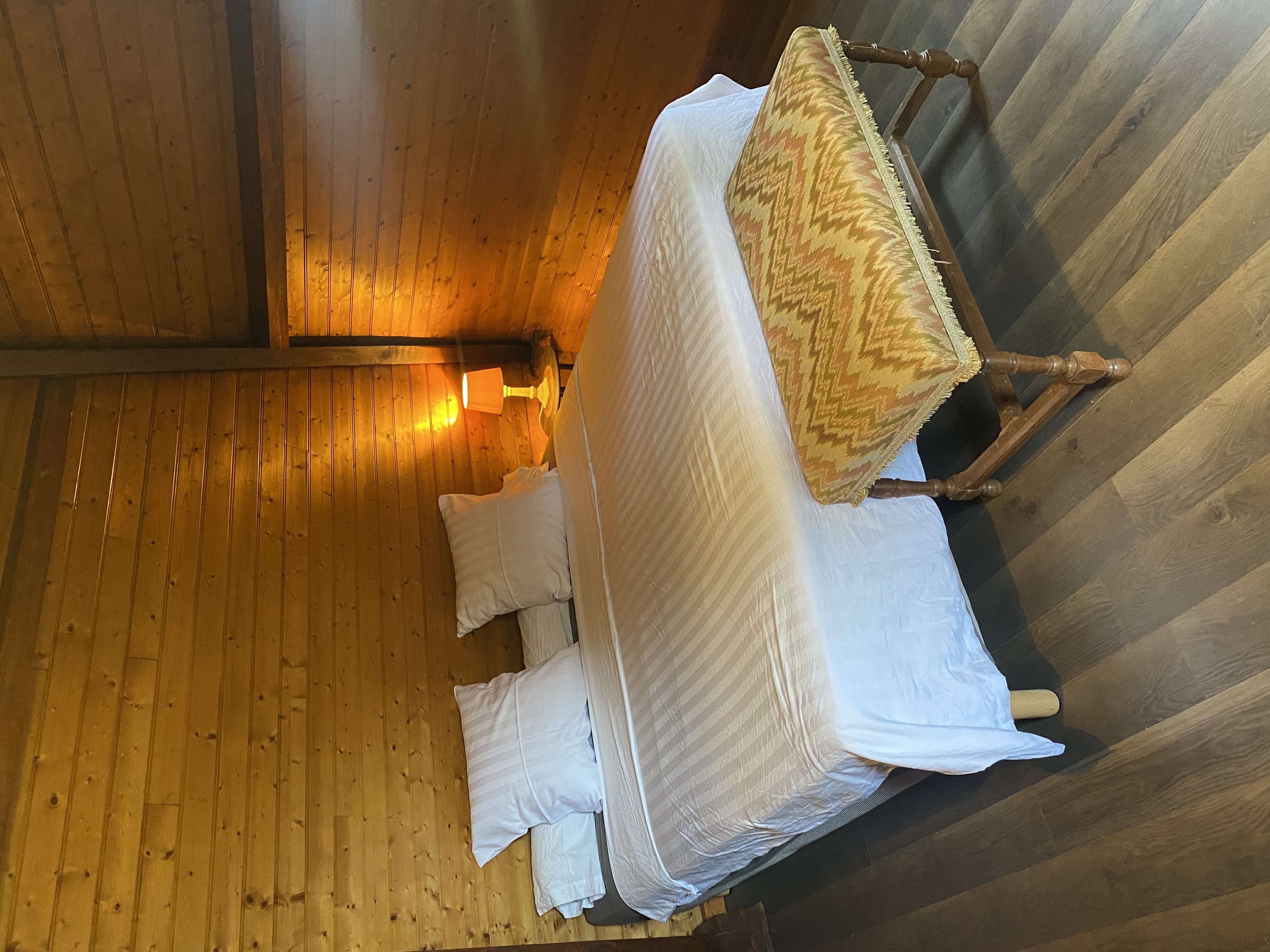 The timber-lined bedroom at Maison des Vignes, with an antique tapestry bench