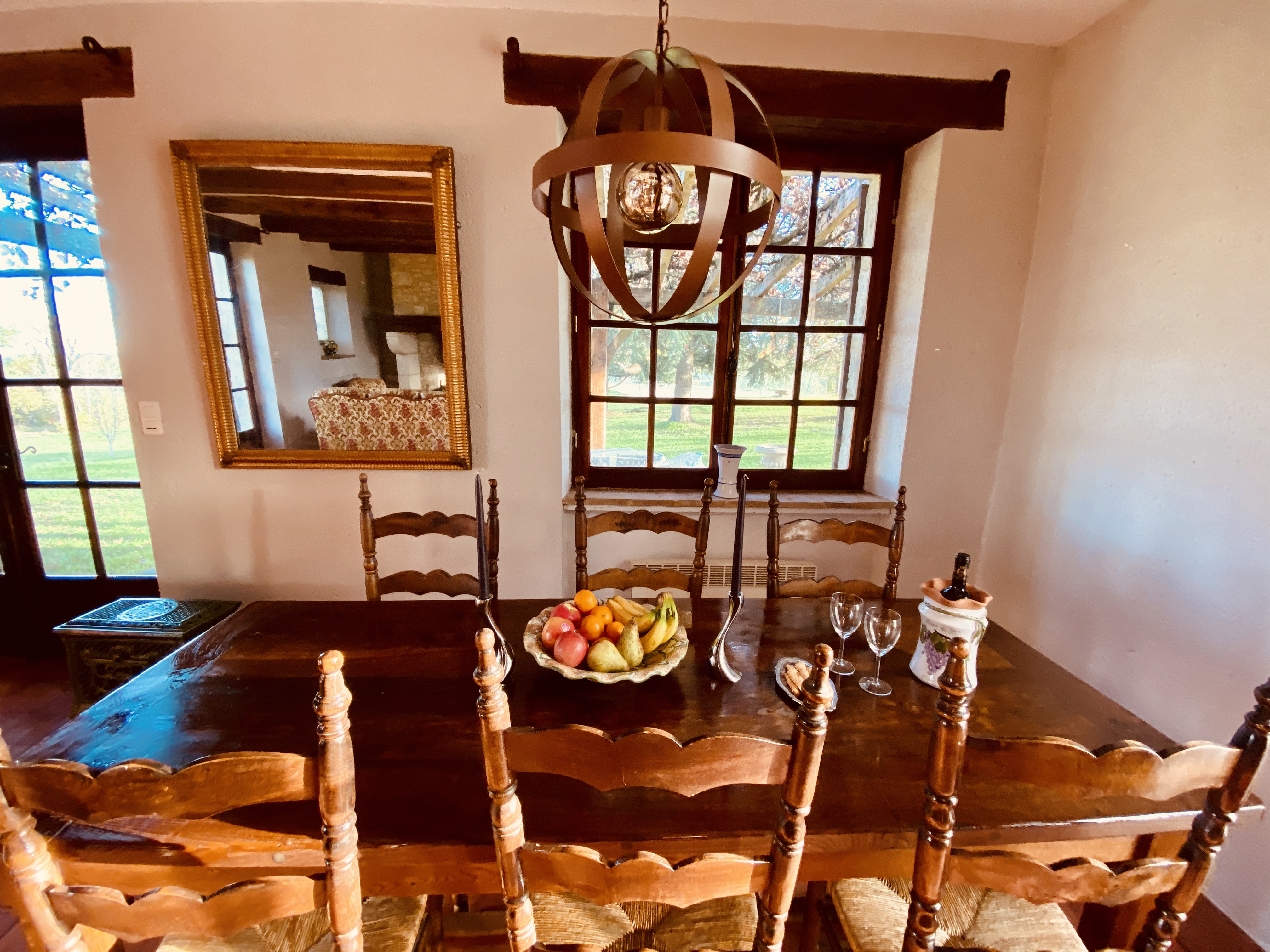The dining room at Maison des Vignes, with a long farmhouse table and gilt mirror