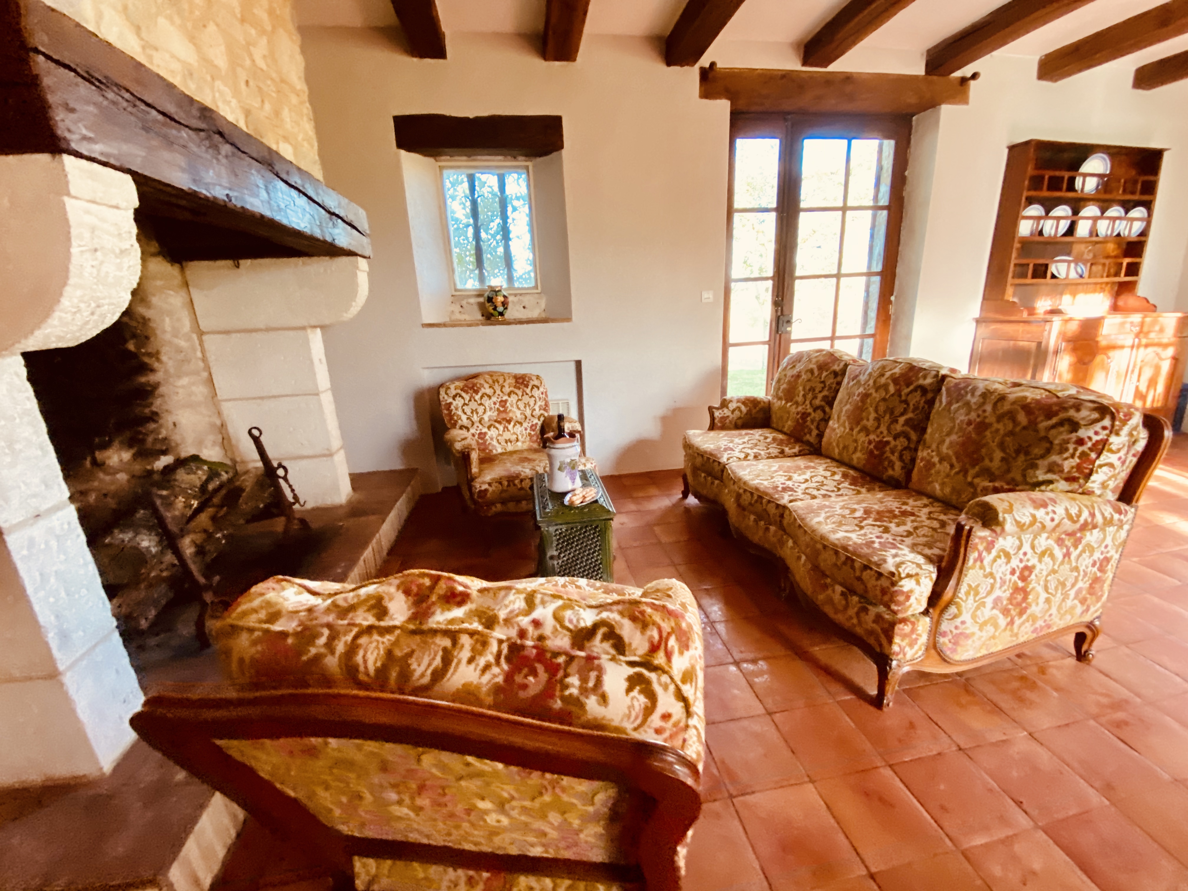 The lounge at Maison des Vignes, with its carved stone fireplace and tapestry sofas