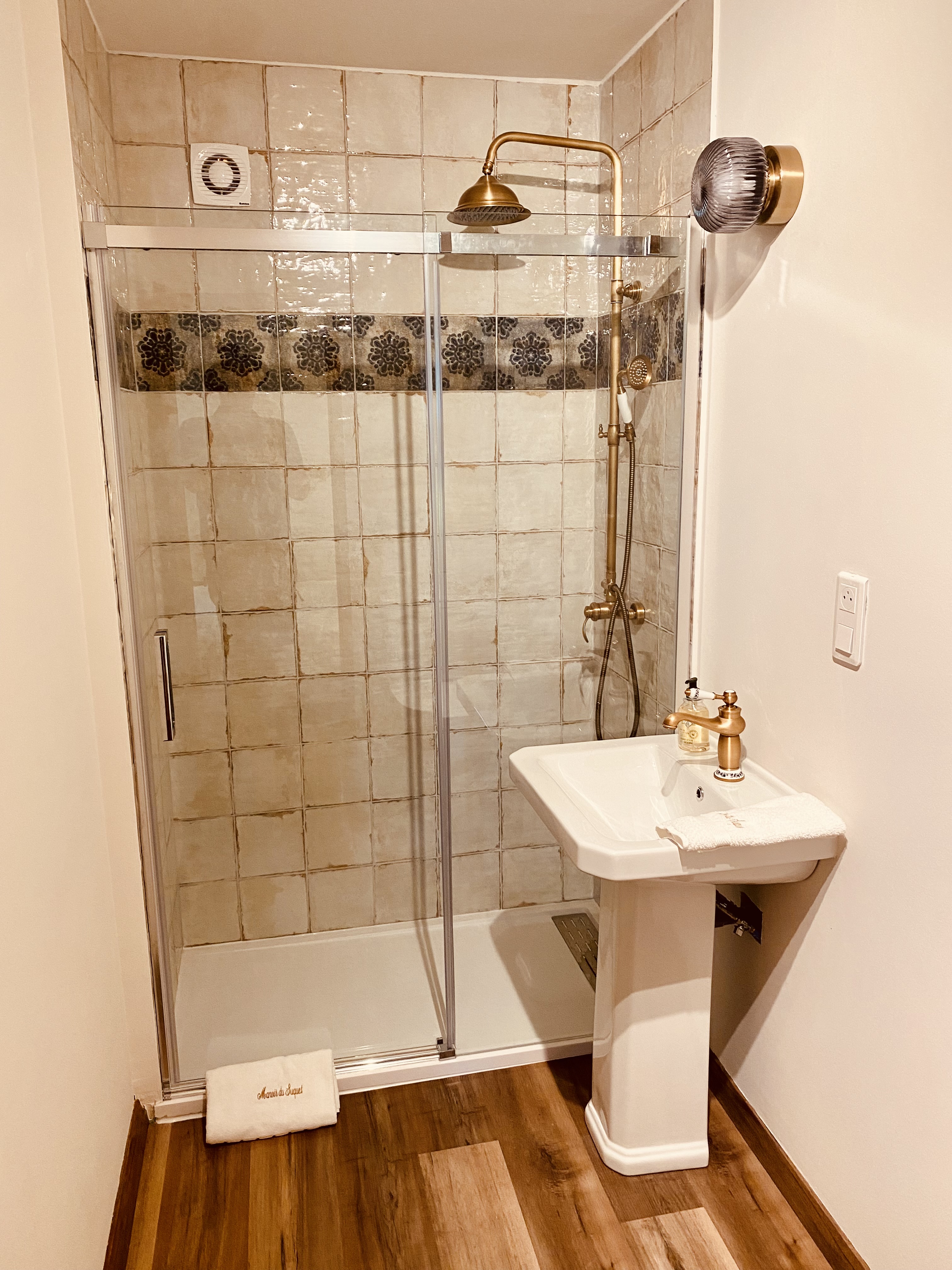 The ground-floor shower room at Maison des Vignes, with brass fittings and a walk-in shower